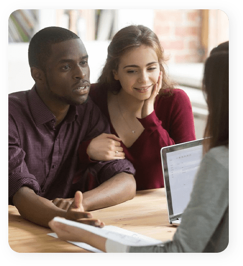 A man and woman sitting at a table with an open laptop.